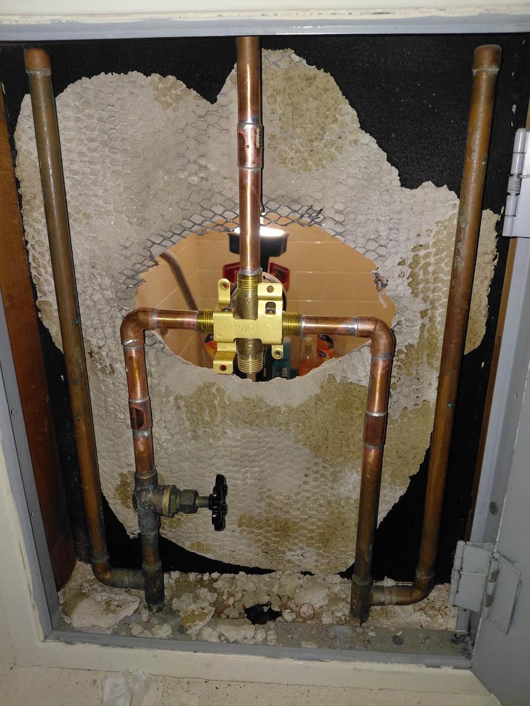 The new mixing valve piped in, seen through the same wall access panel